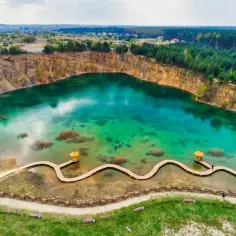 Turkusowe jezioro w kamieniołomie z drewnianą kładką i altaną.